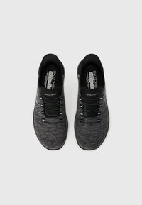 Černé slip-on boty Skechers s texturovaným síťovým svrškem, elastickými tkaničkami a polstrovaným límcem. Významná kombinace šedé a černé barvy.
