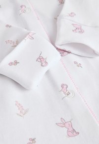 Body en coton blanc avec imprimés d'animaux roses et de fleurs, doté de boutons-pression et de coutures contrastantes roses. Texture douce avec une coupe ajustée.