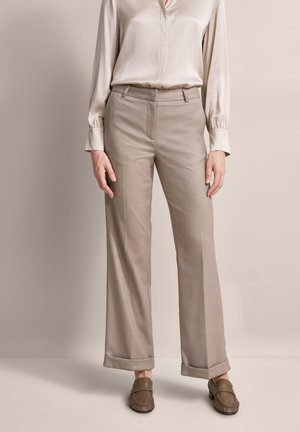 Beige tailored trousers with a straight-leg fit, cuffed hem, and smooth fabric texture, paired with a light-colored satin blouse and brown loafers.