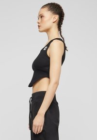 Must mustriba cropped tank top laia rihmadega, koos mustade paelaga dressipüksidega. Omab väikest logo vasakul ülaservas.