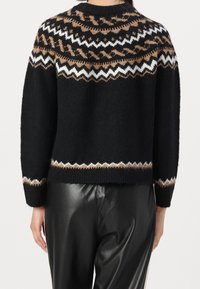 Pull noir en tricot avec un empiècement à motif comprenant des zigzags marron, blancs et beige ; fini avec un ourlet côtelé et des manches longues.