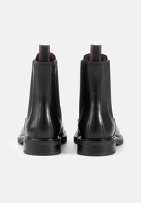 Zwarte leren Chelsea-boots met een slank ontwerp, elastische zijpanelen en een trekhaak aan de achterkant, met een textuur rubberen zool.