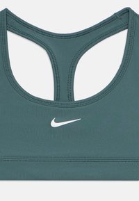 Αθλητικό σουτιέν Nike σε τυρκουάζ χρώμα με σχεδιασμό racerback, με λευκά λογότυπα και λείο, ελαστικό ύφασμα με ορατές ραφές.