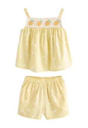 Haut sans manches jaune avec détail brodé de fruits et short jaune assorti à pois blancs, taille élastique sur le short.