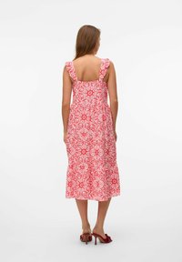 Maxi dress with a ruffled shoulder design, featuring a floral red and white pattern, tiered hem, and open back.