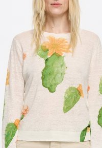 Lichtgewicht, crèmekleurige trui met een cactus en bloemenprint in groen en oranje. Lange mouwen met ribgebreide manchetten.