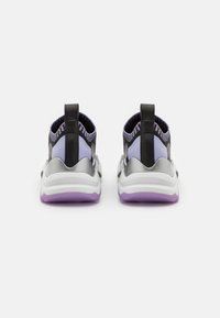 Baskets de sport violettes et noires avec une tige en maille, des accents argentés, une cheville élastique et une semelle épaisse blanche avec une semelle extérieure violette.