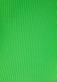 Tissu vert côtelé avec une texture douce, présentant des lignes verticales espacées uniformément. Le matériau semble extensible et léger.
