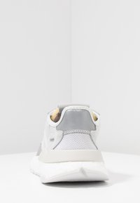 Gray and white athletic shoe with mesh and smooth synthetic upper, unique shape, padded collar, and distinctive white sole design.