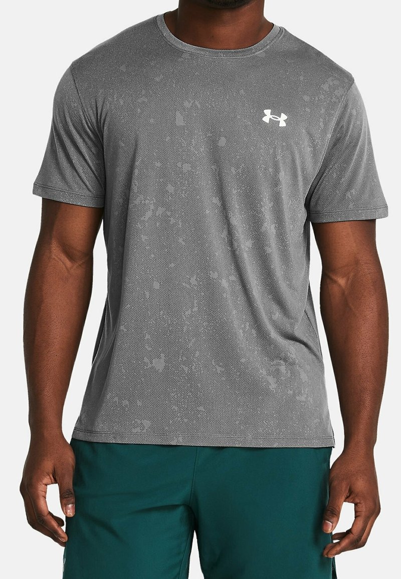 Šedé atletické tričko s krátkým rukávem vyrobené z texturované látky, se subtilním abstraktním vzorem a bílým logem na levé straně hrudi.