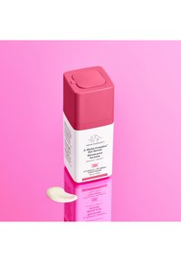 Square, pink and white bottle of A-Shaba Complex™ Eye Serum with a flip-top lid. A small amount of cream is displayed beside it.