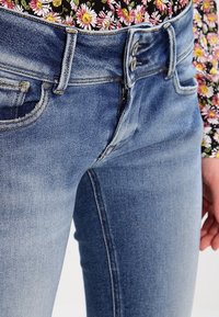 Ljusblå denimjeans med slim fit, tvåknappsstängning och framfickor. Tyget har en mjuk textur och lätt blekning.