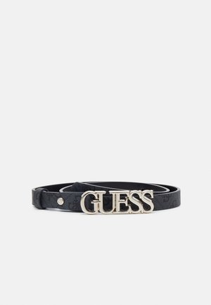 Ceinture en cuir noir avec une boucle en métal argenté formant le mot « GUESS » en lettres épaisses, enroulée sur un fond blanc.
