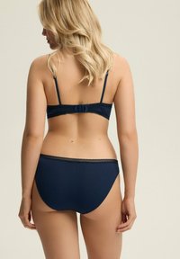 Navyblaues Lingerie-Set mit gerippter Textur, verstellbaren Trägern, Spitzenakzenten und einem Hakenverschluss auf der Rückseite des BHs.