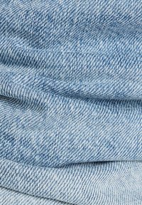 Tissu en denim bleu clair avec une texture douce, présentant un léger tissage en sergé et des variations subtiles de couleur, créant un look classique.