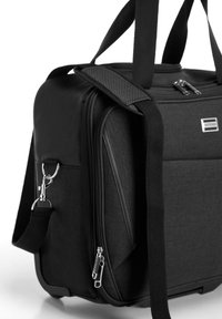 Borsa da viaggio nera con design strutturato, texture in tessuto, doppie cerniere e tracolla staccabile. Presenta una placca con il logo e accessori in metallo.