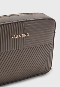 Borsa cosmetica grigia trapuntata con scansioni orizzontali e verticali, con logo "Valentino" in tono oro e superficie testurizzata.