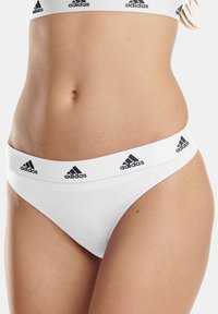 Weiße Baumwollunterwäsche mit einem schwarzen Adidas-Logo am Bund, im klassischen Low-Rise-Design und mit glatter Textur.