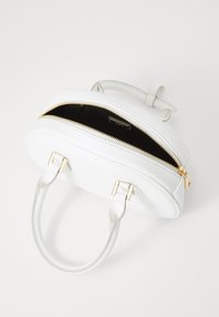 Weiße Handtasche mit goldfarbener Hardware, runder Form, glatter Textur und Reißverschlussverschluss. Der offene Oberteil zeigt das schwarze Innenfutter.