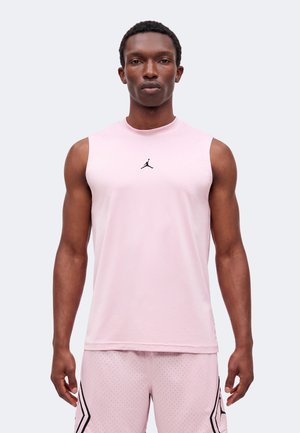 Férfi áll előrenézve, rózsaszín ujjatlan sportpólót viselve fekete Jumpman logóval és hozzáillő rózsaszín perforált rövidnadrágot.