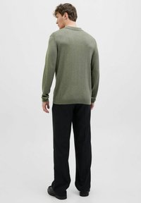 Olīvu zaļš adīts džemperis ar garām piedurknēm un apkakles dizainu, apvienots ar melniem platām biksēm. Strukturēta auduma ar ribotām aprocēm.