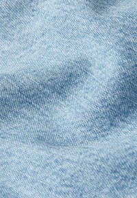 Ljust blå denimtyg med en subtil textur, som har ett vävt mönster och mjuk drapering, som visar fina färgvariationer genom hela tyget.