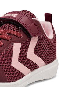 Burgunderfarbene Mesh-Sneaker mit pinken Gummidetails, ausgestattet mit einem Klettverschluss und einer strukturierten Oberseite. Weiße Sohle mit einem Grip-Muster.