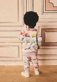 Fleecepulloverwear mit bunten Auto-Mustern, in Hellgrau. Lange Ärmel, gerippte Bündchen und passende Hose mit elastischem Bund.