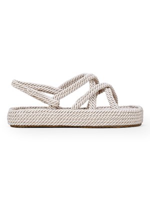 Platte sandaal met gevlochten beige touwbandjes die over de voet kruisen en een gevlochten touwzool, gezien van opzij tegen een witte achtergrond.