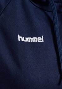 Marinblå hoodie i bomullsblandning med en vit "hummel"-logotyp på bröstet och texturerade snoddar på huvan.