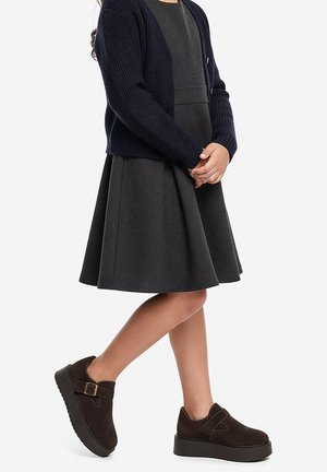 Granatowy dziergany kardigan, szara sukienka z rozkloszowaną spódnicą oraz brązowe zamszowe buty na platformie z paskiem i klamrą.