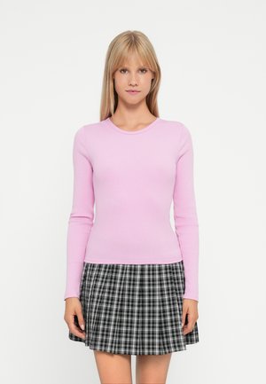 Light pink ribbed long-sleeve top paired with a black and white plaid skirt. The outfit features a round neckline and fits closely.