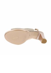 Zapato beige de tacón alto con un empeine de tela texturada y un tacón liso y brillante. La suela presenta un diseño de agarre con patrón.