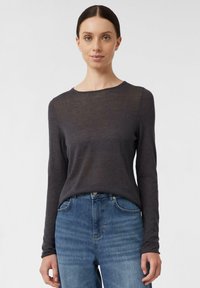 Langarm-Shirt mit Rundhalsausschnitt in Dunkelgrau, aus weichem Stoff. Kombination mit blauen Jeans, Slim Fit und subtile Textur.