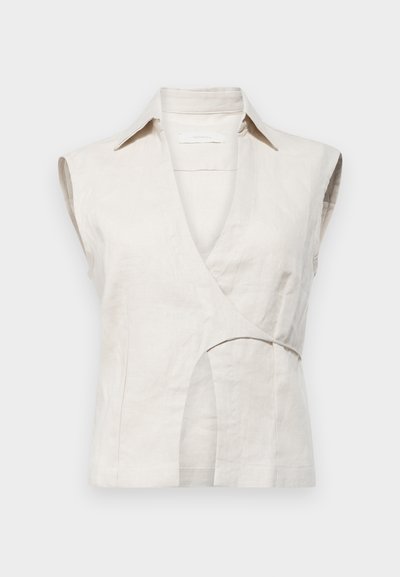 Top de lino beige sin mangas con diseño envolvente y cuello, que presenta un corte en la cintura y una textura suave. Sin cierres visibles.