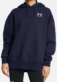 Námorně modrá oversized mikina s kapucí na šňůrku, žebrovanými manžetami a lemem, s bílým logem Under Armour na hrudi. Měkká textura.