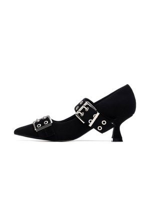 Zapato pump de tacón alto de ante negro con punta puntiaguda, que presenta dos tiras anchas adornadas con hebillas plateadas y ojales, y un tacón afilado.
