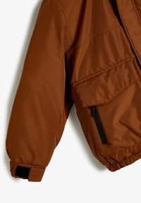 Brun isoleret jakke med en glat tekstur, elastiske manchetter, lynlåslomme og et løst fit design, der har en mat finish.