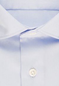 Jasnoniebieska koszula zapinana na guziki z kołnierzykiem, charakteryzująca się gładką teksturą i jednym białym guzikiem przy szyi, z czystym przeszyciem i bez widocznych wzorów.