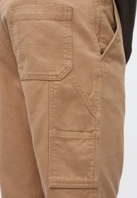 Παντελόνι καμπαρντίνα χακί, από ανθεκτικό βαμβακερό μείγμα, με πολλαπλές τσέπες, ενισχυμένες ραφές και ίσια κοπή.