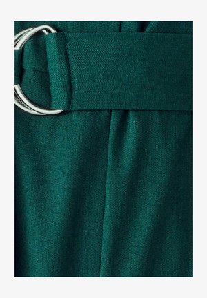 Groene stoffen riem met zilveren dubbele ringgesp op een achtergrond van geplooide groene textuur.