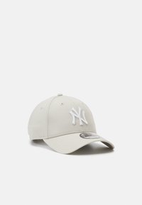 Casquette de baseball beige en coton, avec un logo brodé blanc à l'avant et une visière courbée. Sangle ajustable à l'arrière.