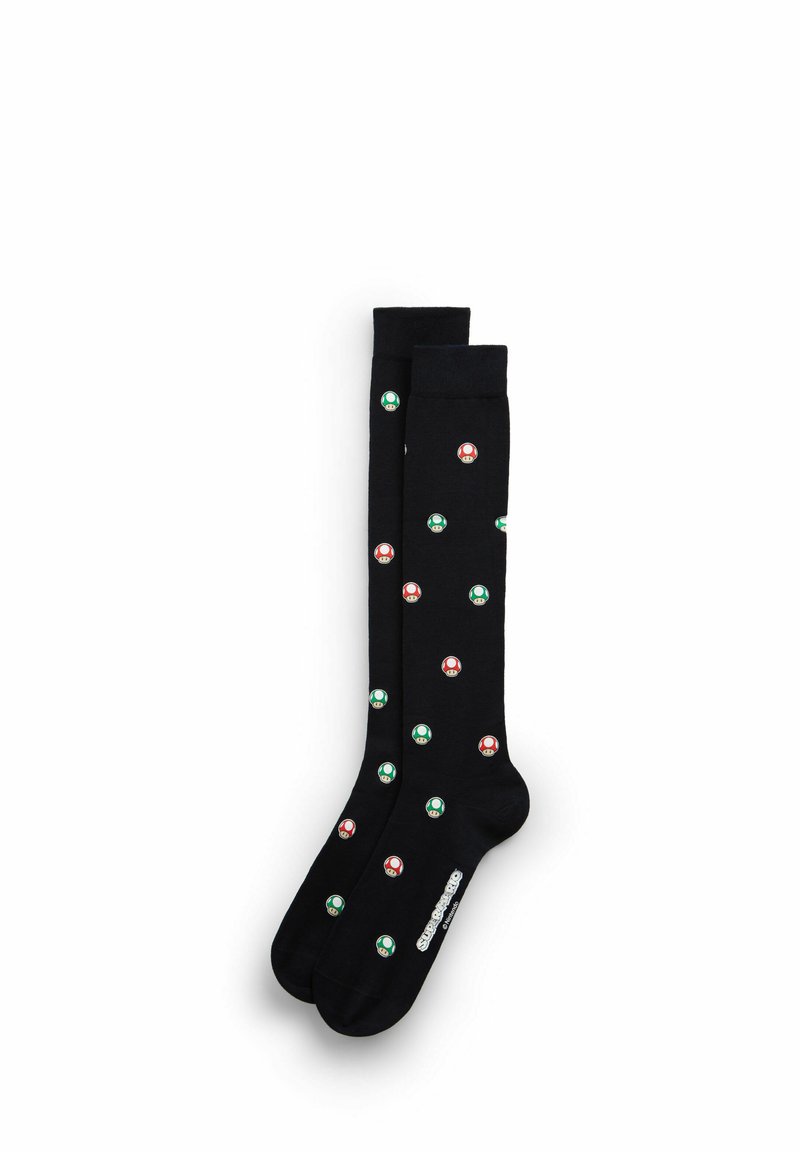 Ponožky ke kolenům z černé bavlny s motivem červených a zelených houbových vzorů. Pevný horní okraj s logem umístěným poblíž kotníku.