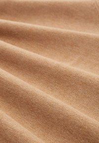 Hellbrauner, strukturierter Stoff mit einer weichen, gewebten Oberfläche, in drapierten Falten dargestellt und zeigt ein glattes und gleichmäßiges Webmuster.