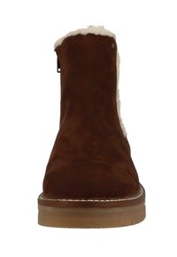 Brązowy zamszowy botek za kostkę z miękkim białym futrem w środku, płaską gumową podeszwą i prostym przeszyciem na krawędzi dla większej trwałości.