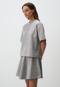 Grijze katoenmix korte mouw top met een ontspannen pasvorm, gelaagd over een bijpassende flared rok. Gladde textuur met minimale naden.