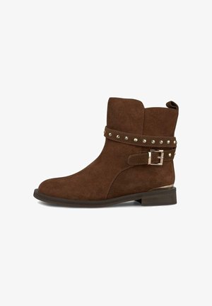 Bottine en daim marron avec un petit talon, sangle décorative avec des clous en argent et boucle métallique sur le côté.