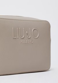 Beige Liu Jo Milano-tas met geprofileerd logo, gestructureerd synthetisch materiaal, rechthoekige vorm en strakke randen.