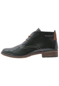 Bottines en cuir verni noir avec des lacets marron et un petit talon. Présente des coutures blanches et un accent de talon marron contrastant.