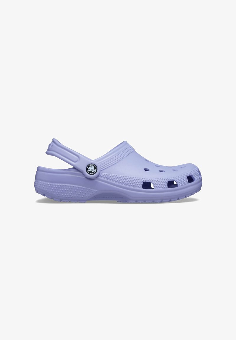 Sabots Crocs en lavande, fabriqués en mousse légère, avec des trous de ventilation, une sangle texturée et un logo de marque sur le côté.